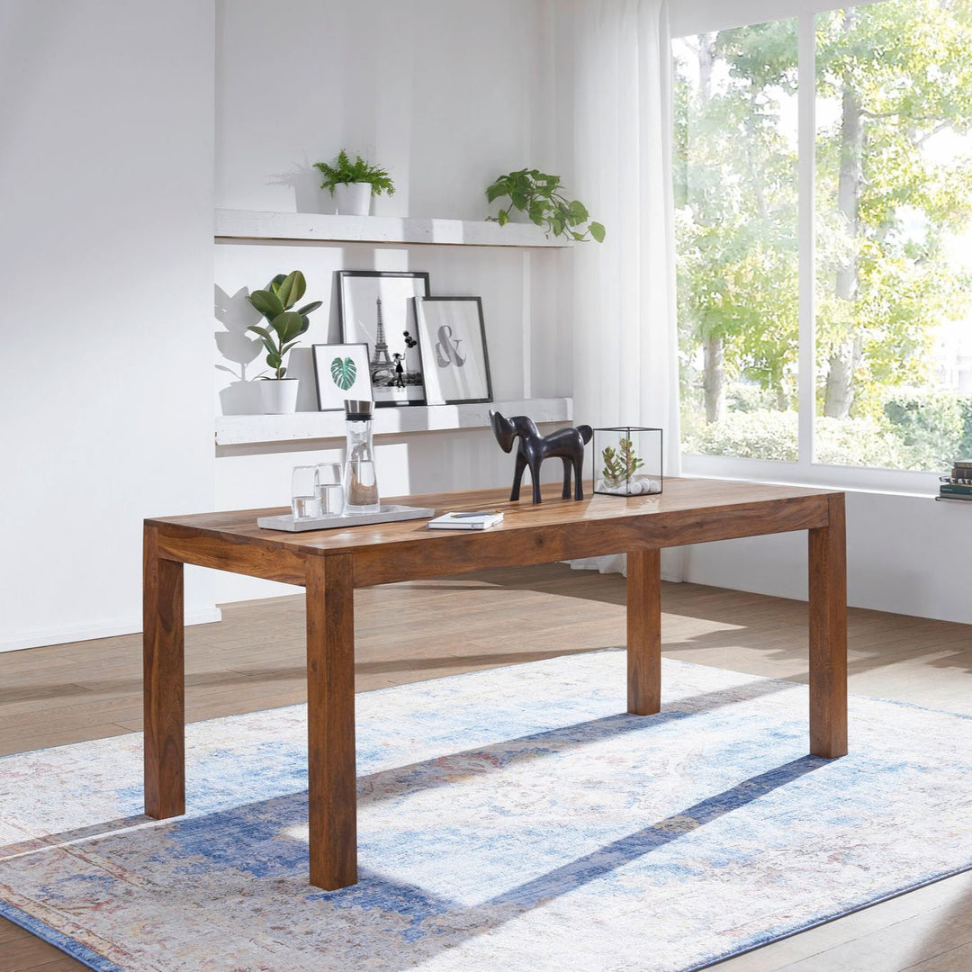 Spisebord i massivt brunt træ med smalle ben placeret i lyst rum med planter og floating shelves