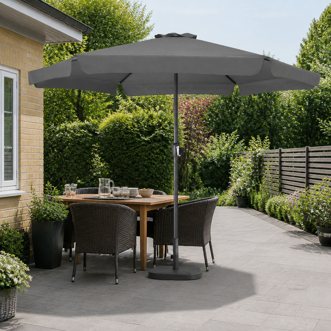 den store antracitgrå parasol i bred, almindelig dansk terrasse, hvor parasollen står sikkert over spisezonen med en separat tung fod og en fri flytterute