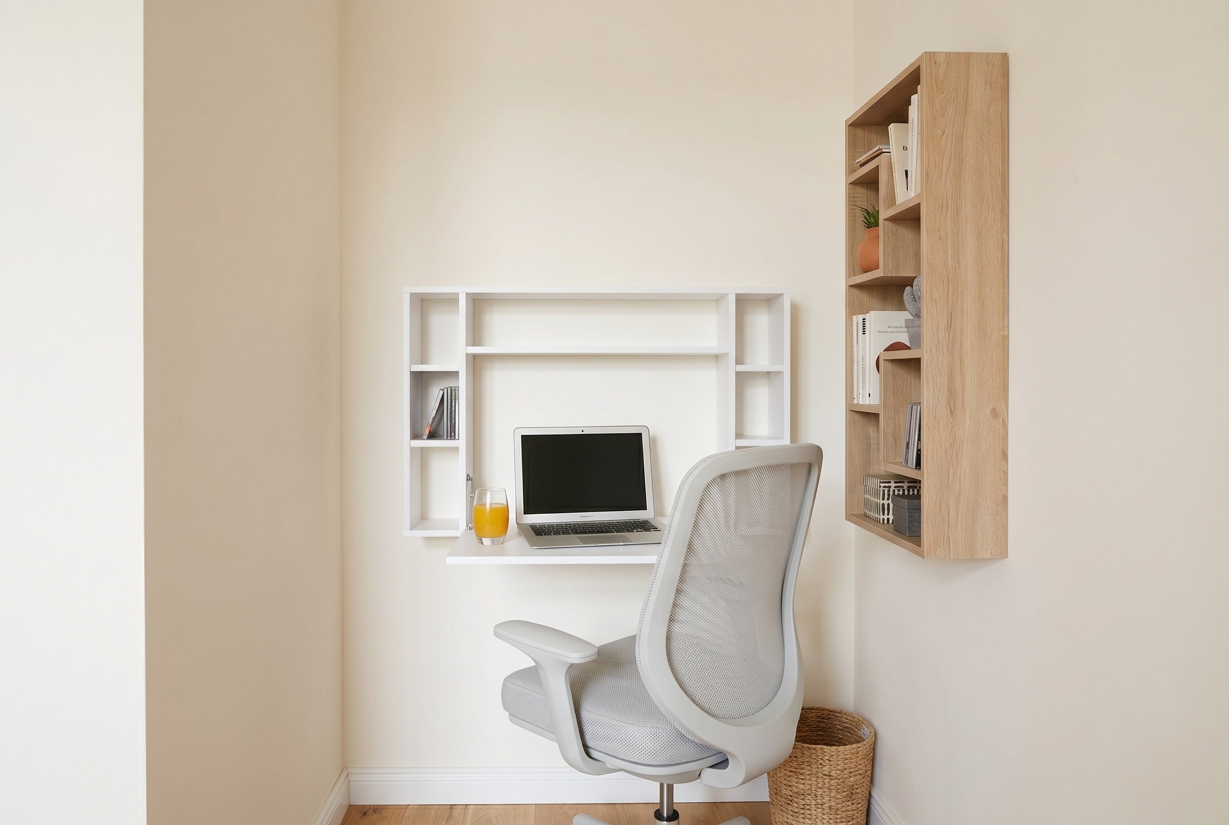 Lille hjemmekontor i et hjørne med foldbart vægskrivebord, grå ergonomisk kontorstol og hængende træreol