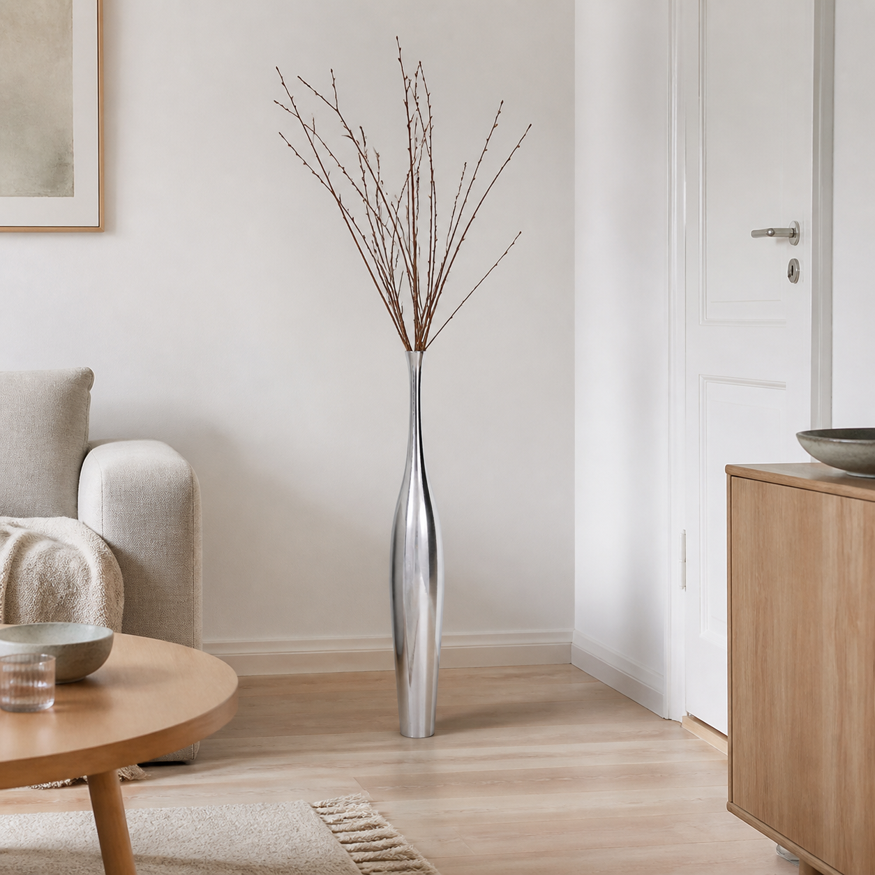 Vasen der giver høje grene ro vist med Blomstervase i aluminium, sølvfarvet i et realistisk, beboet dansk hjem