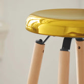 Trendy barstol med guldfarvet metalsæde og stoleben i naturfarvet bøgetræ