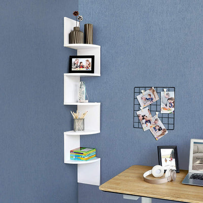 5 hvide svævende væghylder i zigzag-design monteret ved siden af kontorbordet med bøger og rammer